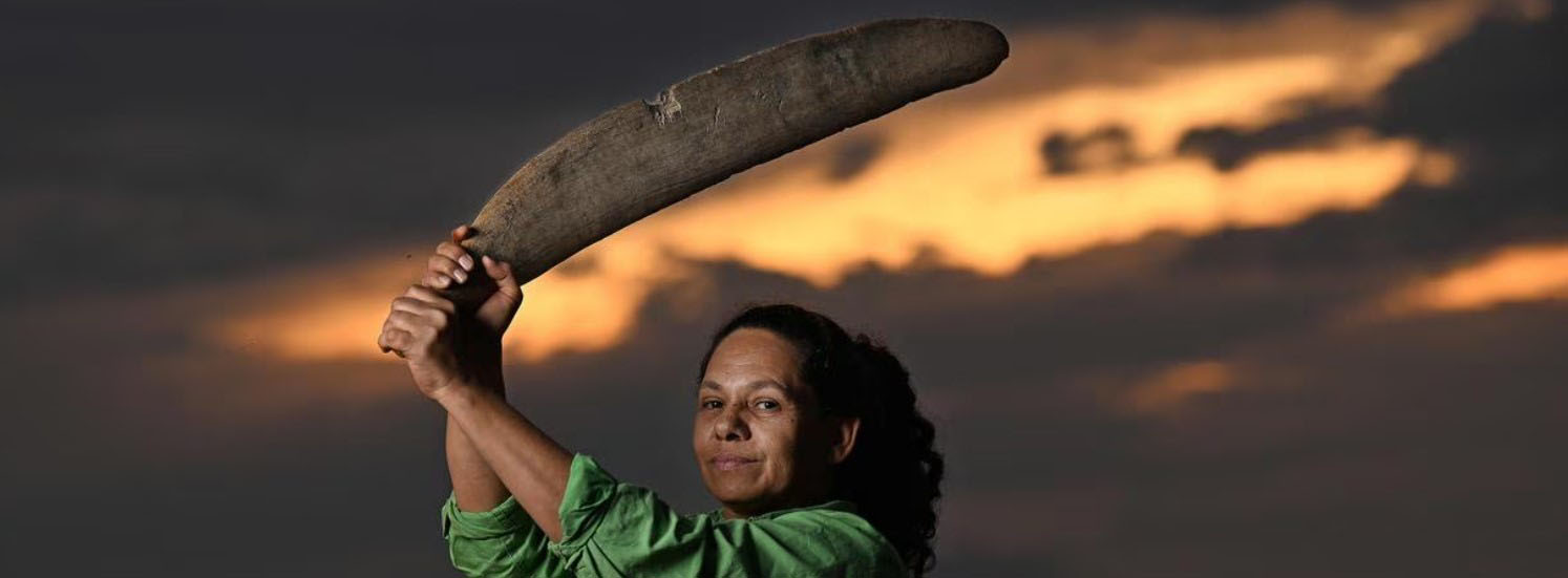 Aboriginal Australian woman holding traditional wooden sword weapon