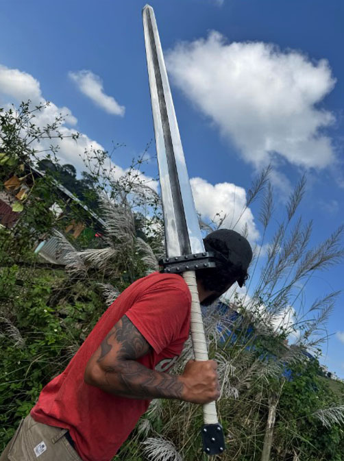 Hand-forged Guts Raider greatsword carried on the shoulder, showing its real size against a man