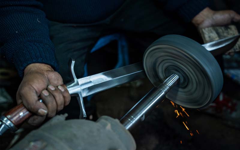 Hand sharpening a forged blade at Everest Forge — honing the edge of a sword, kukri or machete to working sharpness in Kathmandu, Nepal