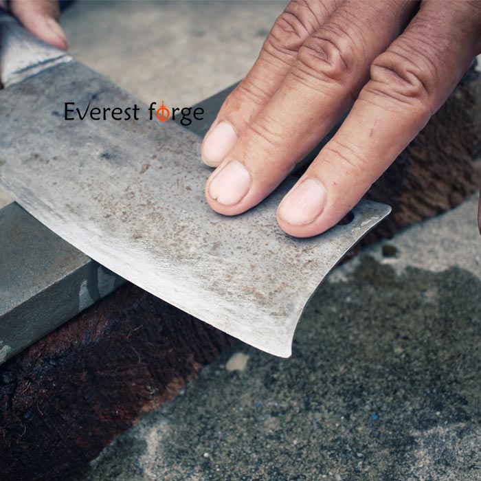 Knife blade being drawn across sharpening stone placed below for consistent angle