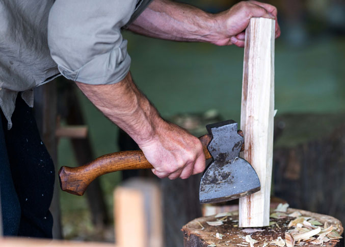 Hand-forged axe slicing wood during bushcraft work