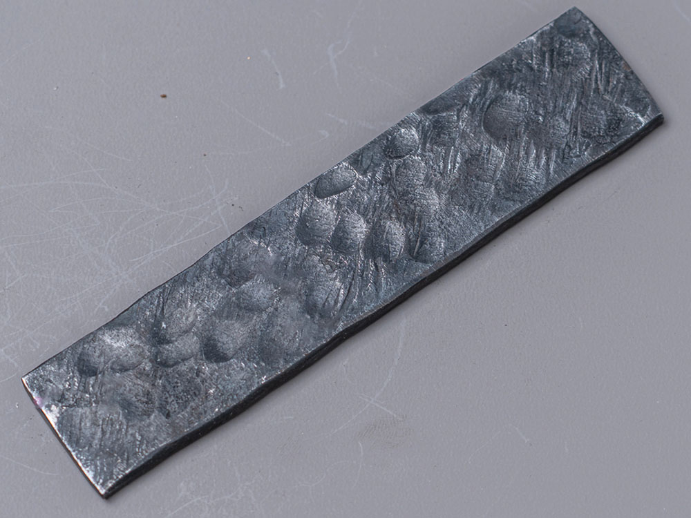 Raw finish blade with a dark, hammered, as-forged texture