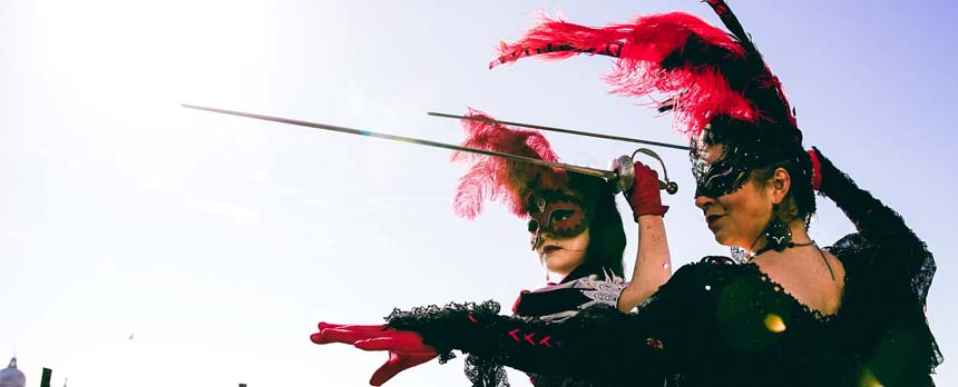 Women in Venice Carnival wearing traditional masks and holding Italian swords